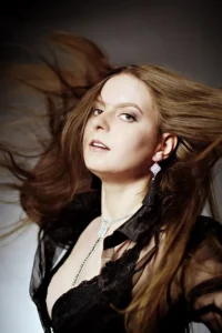 Dramatyczne ujęcie kobiety w czerni, z dynamicznie rozwianymi włosami i odważnym spojrzeniem