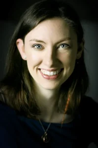 Kobieta z szerokim uśmiechem, w naturalnym świetle, patrząca prosto w obiektyw