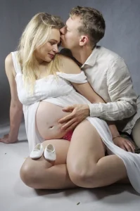 Mężczyzna obejmujący ciężarną partnerkę, ich dłonie spoczywają na brzuchu