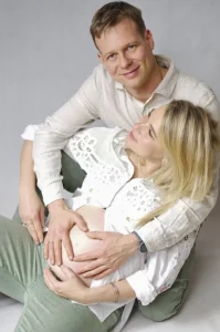 Para w czułym uścisku, trzymająca ręce na brzuszku kobiety w ciąży