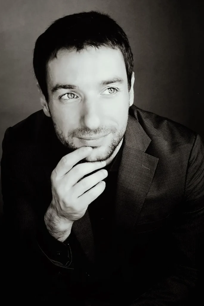 Stylowy portret mężczyzny w czarnej marynarce, patrzącego w dal z lekkim uśmiechem