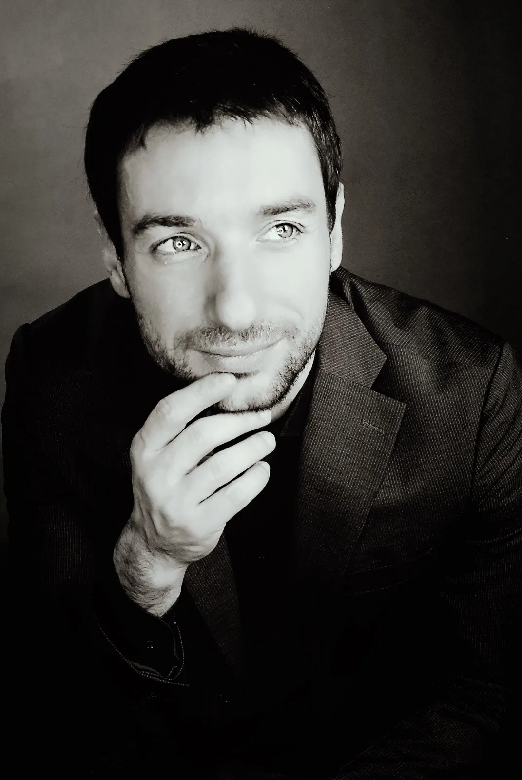 Stylowy portret mężczyzny w czarnej marynarce, patrzącego w dal z lekkim uśmiechem