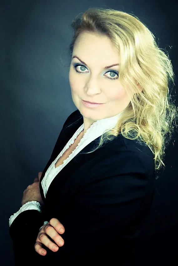 Portret pewnej siebie kobiety w czarnym stroju, z delikatnym uśmiechem