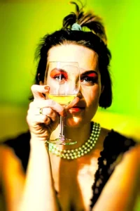 Artystyczna fotografia kobiety trzymającej kieliszek wina na zielonym tle