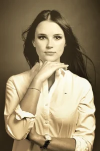 Sepiowy portret młodej kobiety w białej koszuli, patrzącej z zadumą